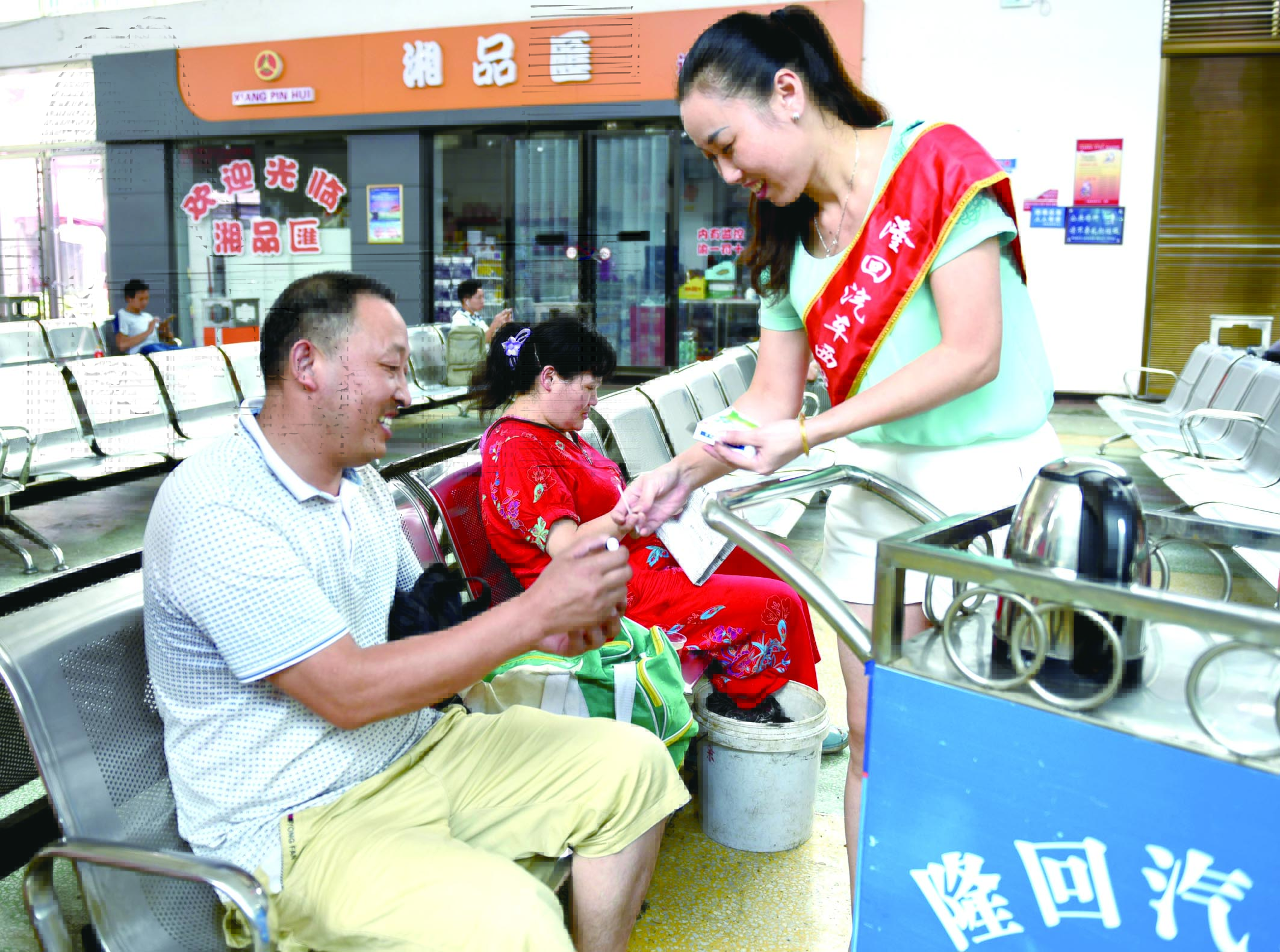 隆回分公司汽車西站工作人員正在為旅客免費贈送藿香正氣水。